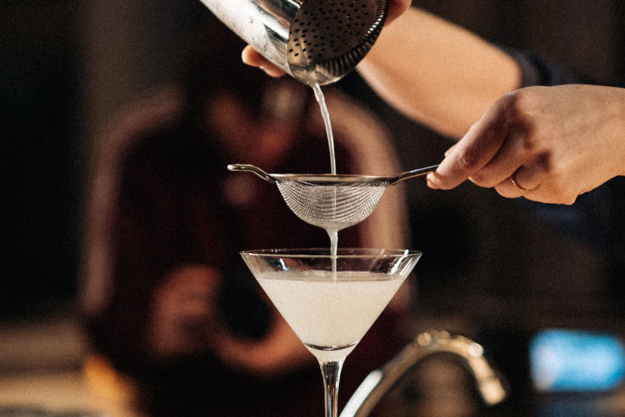 eine Person, die Flüssigkeit in ein Martini-Glas gießt